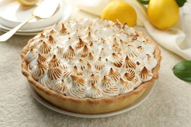 Lezzetli kremalı turta ve bej desenli masada limonlar, yakın plan.