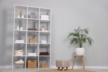 Açık gri duvarın yanında dekorlu raf ünitesi