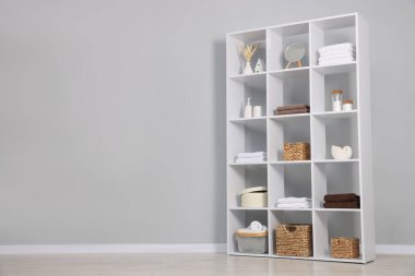 Açık gri duvarın yanında dekorlu raf ünitesi. Metin için boşluk