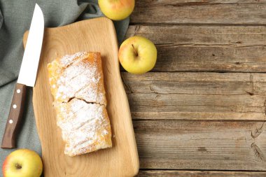 Elmalı lezzetli turta, pudra şekeri ve tahta masa üzerinde bıçak, düz yatak. Metin için boşluk