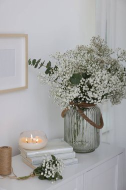 Güzel çigila çiçekleri ve okaliptüs dalları vazoda iç çekmecelerin üzerindeki dekoratif elementlerin yanında.