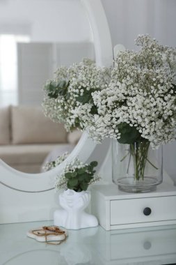 Güzel çigila çiçekleri ve okaliptüs dalları vazoda aynanın yanındaki tuvalet masasında.
