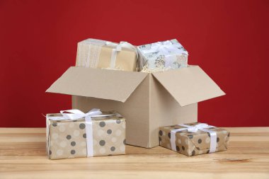 Kırmızı arkaplana karşı ahşap masada hediye kutuları olan paket