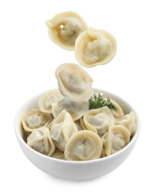 Lezzetli haşlanmış hamur tatlısı (pelmeni) beyaz arka planda kaseye düşüyor