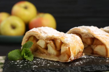 Lezzetli elmalı turta parçaları pudra şekeri ve nane şekeri ile siyah arka planda, yakın plan.