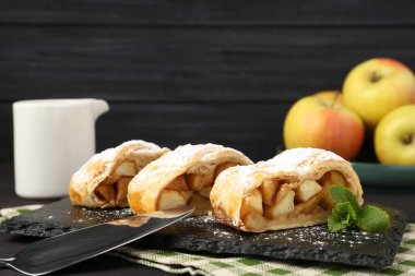 Lezzetli elmalı turta parçaları pudra şekeri ve siyah masada nane şekeri, yakın plan.