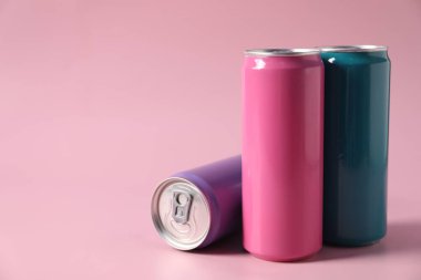 Pembe zemin üzerinde renkli alüminyum içecek kutuları, metin için boşluk