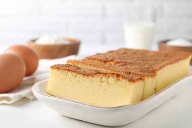 Lezzetli Japon Castella sünger keki ve malzemeler beyaz masada, yakın plan.