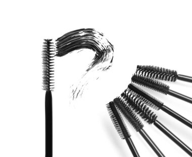 Maskara lekesi ve beyaz arka planda farklı fırçalar, üst manzara. Dekoratif kozmetik