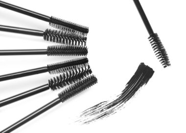 Maskara lekesi ve beyaz arka planda farklı fırçalar, üst manzara. Dekoratif kozmetik