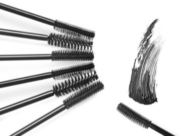 Maskara lekesi ve beyaz arka planda farklı fırçalar, üst manzara. Dekoratif kozmetik