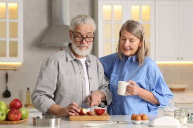 Sevimli yaşlı çift mutfaktaki masada birlikte yemek pişiriyor.