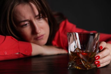 Alkol bağımlılığı. Masasında viski olan zavallı kadın. Karanlık, seçici bir odak noktası.