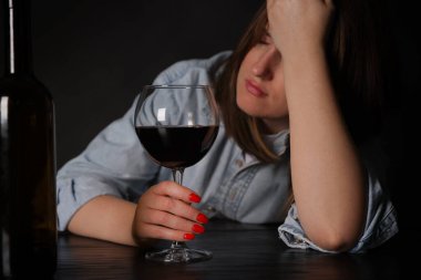 Alkol bağımlılığı. Karanlıkta şarap içen sefil kadın.