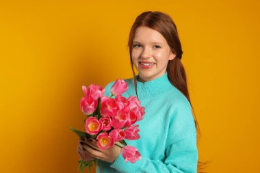 Turuncu arka planda bir buket lale ile güzel bir genç kız.