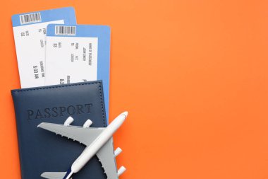 Seyahat acentesi. Uçuş biletleri, pasaport ve turuncu arka planda uçak modeli. Metin için boşluk