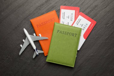 Seyahat acentesi. Uçuş biletleri, pasaportlar ve uçak modeli koyu dokulu masa, düz yatış