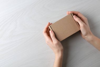 Beyaz ahşap arka planda boş karton kutulu kadın, üst manzara. Tasarım için model