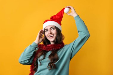 Turuncu arka planda Noel Baba şapkası olan mutlu bir genç kadın.