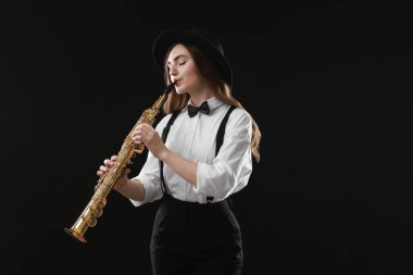 Koyu arkaplanda soprano saksafon çalan müzisyen.