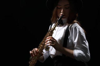 Karanlık arka planda soprano saksafon çalan müzisyen, yakın plan. Metin için boşluk