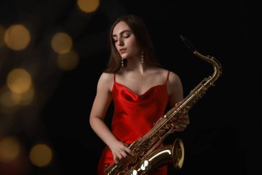 Siyah arka planda bulanık ışıklarla saksafon çalan profesyonel bir müzisyen. Bokeh etkisi