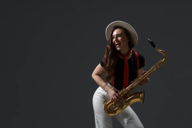 Gri arka planda saksafonu olan profesyonel bir müzisyen. Metin için boşluk