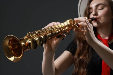 Gri arkaplanda soprano saksafon çalan müzisyen