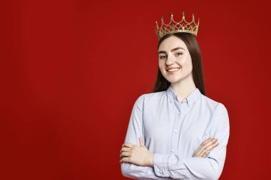 Koyu kırmızı arka planda zarif taç giymiş gülümseyen kadın. Metin için boşluk