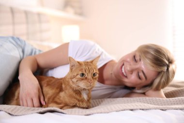 Evde yatağında kızıl kedisi olan, seçici odaklı bir kadın.