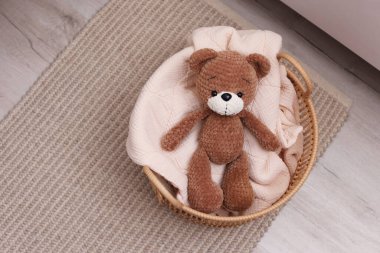 Battaniyeli ve oyuncak ayılı hasır sepet içeride, üst tarafta.