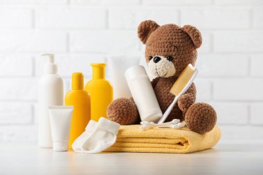 Bebek kozmetik ürünleri, çoraplar, havlu ve oyuncak ayı beyaz tuğla duvara karşı ahşap masada