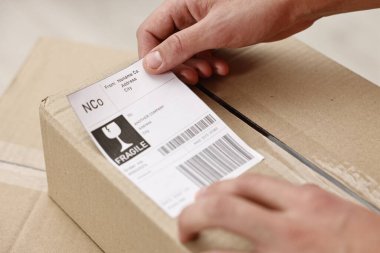 Kapalı mekanlarda barkodlu nakliye etiketi yapıştıran adam.