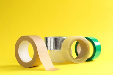 Sarı arka planda farklı yapışkan bantların ruloları