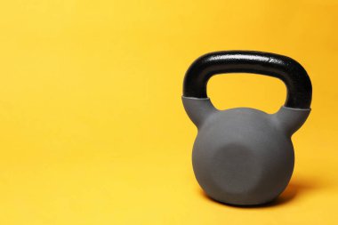 Sarı arka planda ağır bir kettlebell. Metin için boşluk