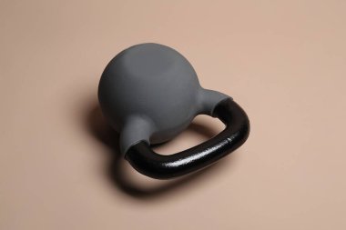 Bej arka planda ağır bir kettlebell. Spor malzemeleri.