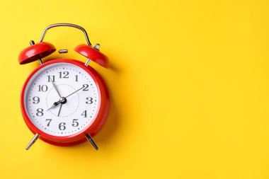 Sarı arka planda kırmızı alarm saati, üst manzara. Metin için boşluk