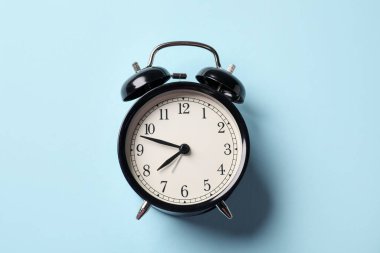 Açık mavi arkaplanda siyah alarm saati, üst görünüm