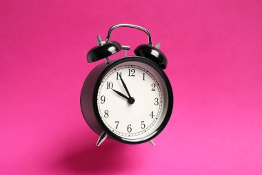 Parlak pembe arka planda siyah çalar saat