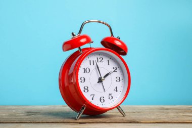 Ahşap masada açık mavi zemin üzerinde bir kırmızı alarm saati