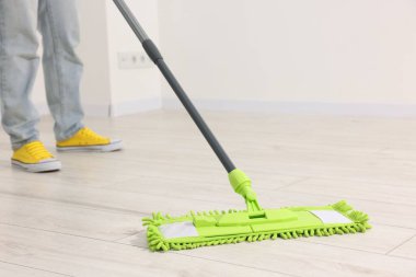 Yerleri mikrofiber paspasla temizleyen kadın, yakın plan.