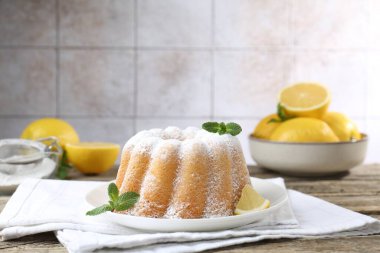 Pudra şekerli lezzetli limonlu pasta, taze meyve dilimi ve ahşap masada nane.