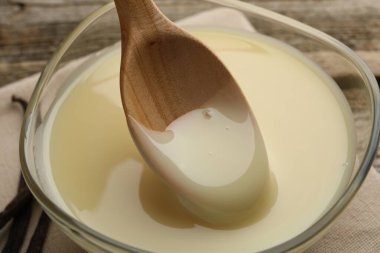 Lezzetli vanilyalı yoğurtlu sütü ahşap masadaki kaşıkla yakın plan çekiyoruz.