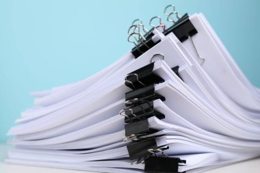 Açık mavi arkaplan üzerine kağıt sayfaları ile cilt ataçları, yakın plan