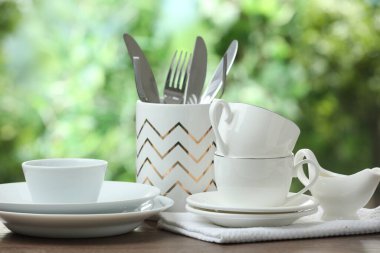 Clean dishware on wooden table against blurred background