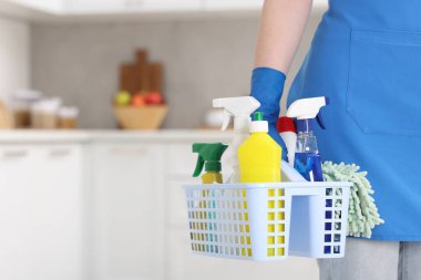 Evde bir sepet temizlik malzemesi olan bir kadın, yakın çekim. Metin için boşluk