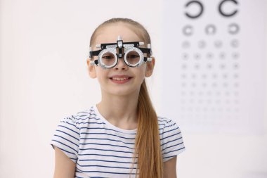 Göz doktorunun muayenehanesinde görüş testinin yanında mahkeme çerçevesi olan küçük bir kız.