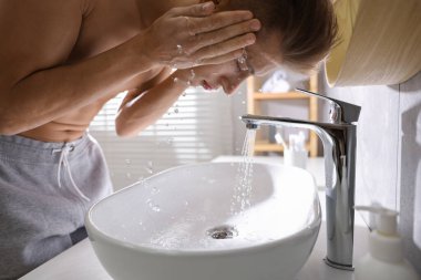 Tuvalette yüzünü yıkayan bir adam.