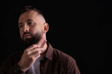 Siyah arkaplanda sakal tarayan yakışıklı adam, metin için boşluk