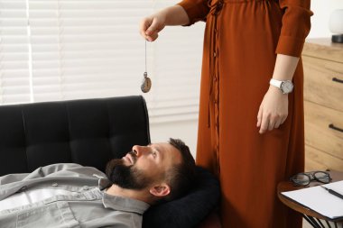 Psikolog, hipnoz seansı sırasında hastayla çalışırken kapalı kapılar ardında antika cep saati kullanıyor.